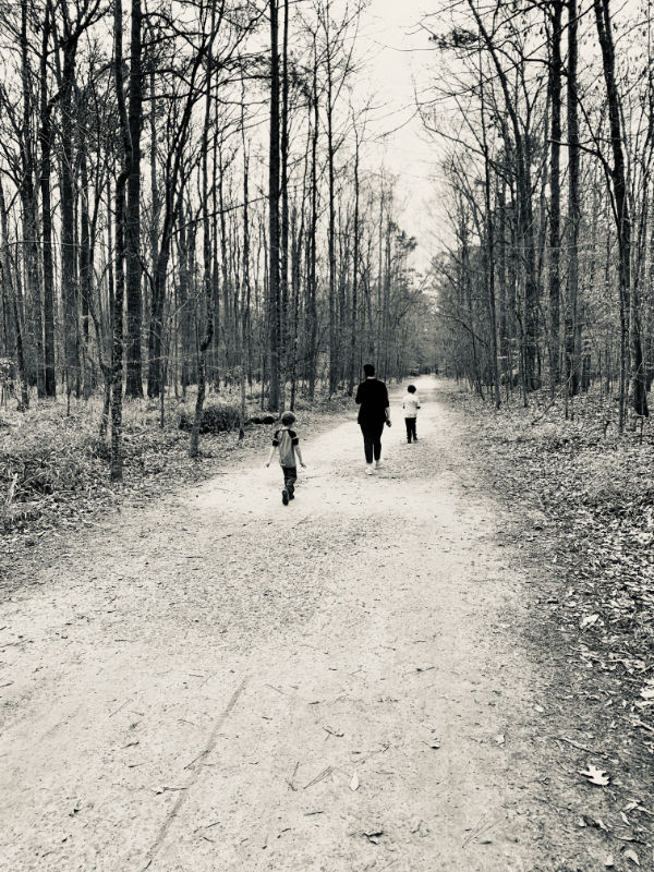 A mother and her children walking along a dirt road.